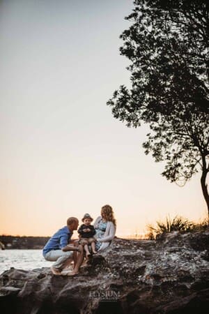 Maternity session - a family sit around the pregnant mother as the sun sets behind them