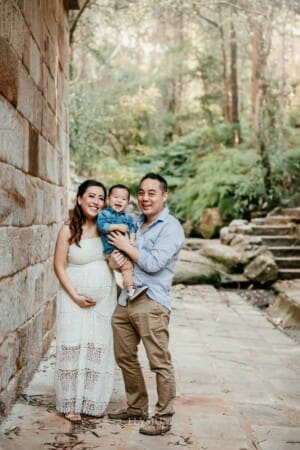 Family session - parents stand hugging their son against a sandstone wall
