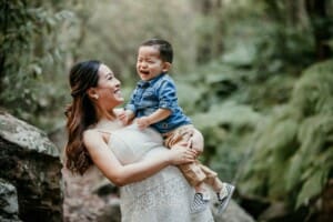 Maternity session - A pregnant woman holds her little boy as they both giggle