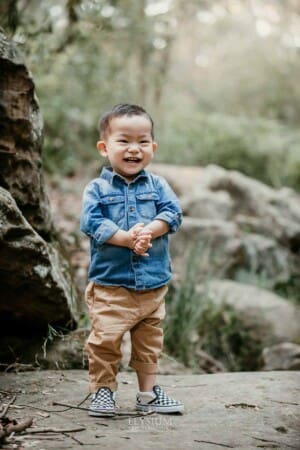 Family Session - A little boy giggles while standing on river rocks