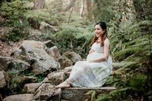 Maternity Session - A pregnant mother holds her belly sitting on sandstone steps