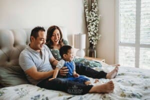 Newborn session - parents sit on a bed with their little boy in their lap