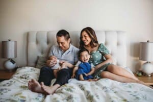 Newborn session - a family sitting on a bed adoring their newborn baby boy