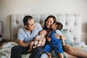Newborn session - a little boy kisses his mum's cheek, sitting next to his newborn brother
