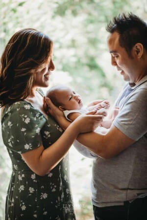 Newborn session - Parents stand holding their newborn son between then