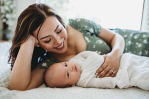 Newborn session - a mother lays next to her newborn baby boy, cuddling him