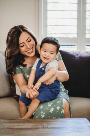 Newborn session - a mother cuddles her giggling baby boy in her lap