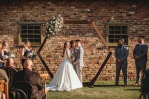 Gledswood Wedding - bride and groom stand under their ceremony arch
