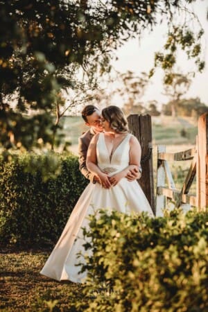 Gledswood Wedding - bride and groom stand cuddling against an old gate
