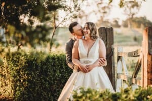 Gledswood Wedding - bride and groom stand cuddling against an old gate