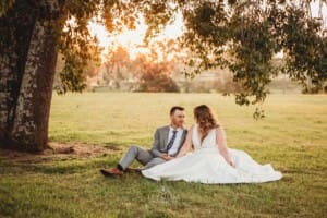 Gledswood wedding - bride and groom sit under a tree in the venue gardens