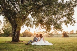 Gledswood wedding - bride and groom sit under a tree in the venue gardens