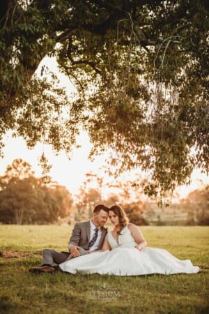Gledswood wedding - bride and groom sit under a tree in the venue gardens