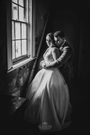 Gledswood wedding - bride and groom stand next to a window in the homestead venue
