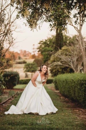 Gledswood wedding - bride laughs as she stands in the venue gardens