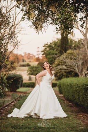 Gledswood wedding - bride laughs as she stands in the venue gardens