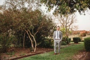 Gledswood wedding - groom stands in the venue garden at sunset