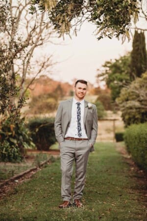 Gledswood wedding - groom stands in the venue gardens at sunset