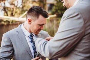 Gledswood Wedding - groomsman fixes the groom's button flower