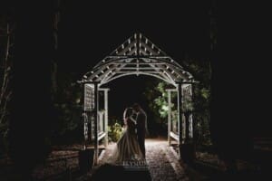 Gledswood wedding - night time shot of newlyweds standing under an arbour