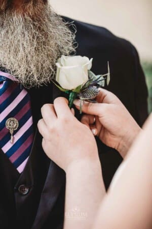 Gledswood Wedding - bride pins the buttonhole flower to her father's suit