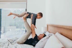 Newborn session - a father and son play together on a bed