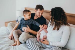 Newborn session - a little boy touches his baby brother on the cheek