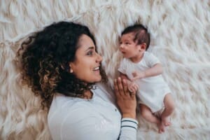 Newborn session - a mother lays with her baby on a bed