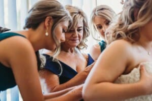 Gledswood Wedding Photo - Bridesmaids help tie the bridal gown
