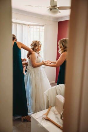 Gledswood Wedding Photo - Bridesmaids help tie the bridal gown