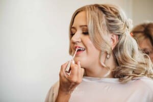 Gledswood Wedding Photo - makeup artist applies lipstick to the bride