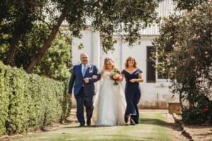Gledswood Wedding Photo - bride walks down the aisle to the ceremony with her parents