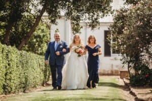 Gledswood Wedding Photo - bride walks down the aisle to the ceremony with her parents