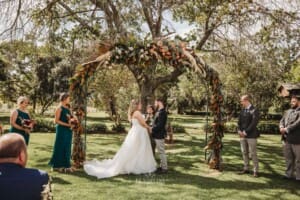Gledswood Wedding Photo - bride and groom stand under the arch during the ceremony