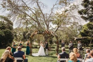 Gledswood Wedding Photo - bride and groom stand under the arch during the ceremony