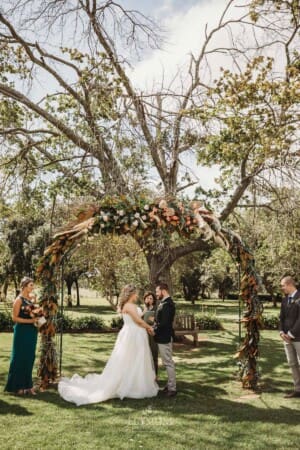 Gledswood Wedding Photo - bride and groom stand under the arch during the ceremony