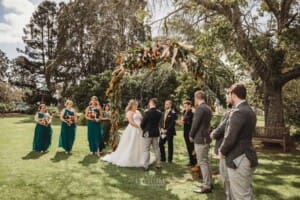Gledswood Wedding Photo - bride and groom stand under the arch during the ceremony