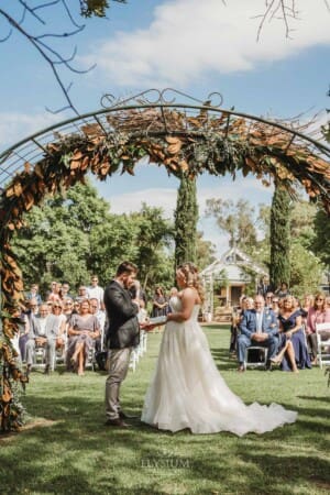 Gledswood Wedding Photo - bride and groom stand under the arch during the ceremony