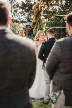 Gledswood Wedding Photo - bride and groom stand under the arch during the ceremony