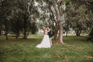 Gledswood Wedding Photo - groom kisses his bride as they stand in the homestead grounds