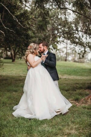 Gledswood Wedding Photo - groom hugs his bride as they stand in the homestead grounds