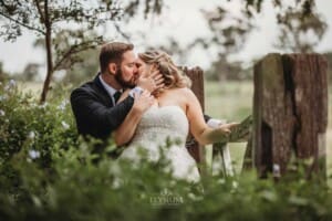 Gledswood Wedding Photo - bride and groom kiss standing at a farm gate