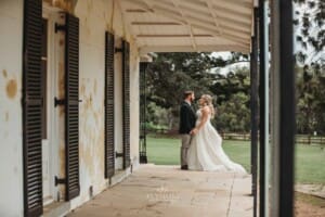 Gledswood Wedding Photo - bride and groom hold hands standing on the homestead veranda