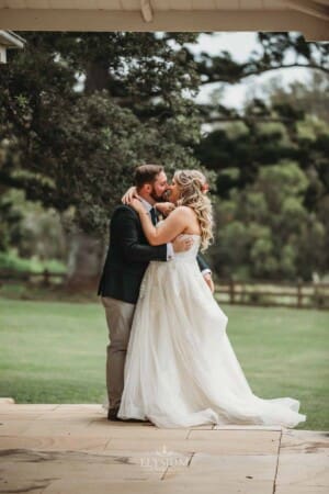 Gledswood Wedding Photo - bride and groom kiss standing on the homestead veranda