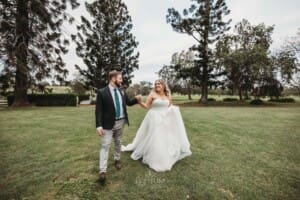 Gledswood Wedding Photo - bride and groom walk across the homestead lawn