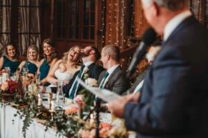 Gledswood Wedding Photo - bride and groom laugh as the groom's father makes his speech
