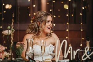 Gledswood Wedding Photo - the bride grins as the groom makes his speech