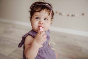 Cake Smash Session - baby girl tastes a handful of pink icing