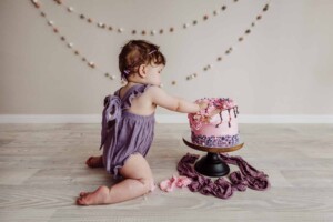Cake Smash Session - baby girl plunges her hand into her birthday cake