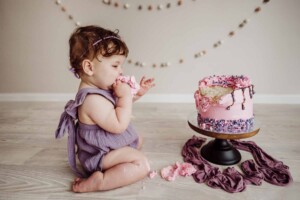 Cake Smash Session - baby girl tastes a handful of cake